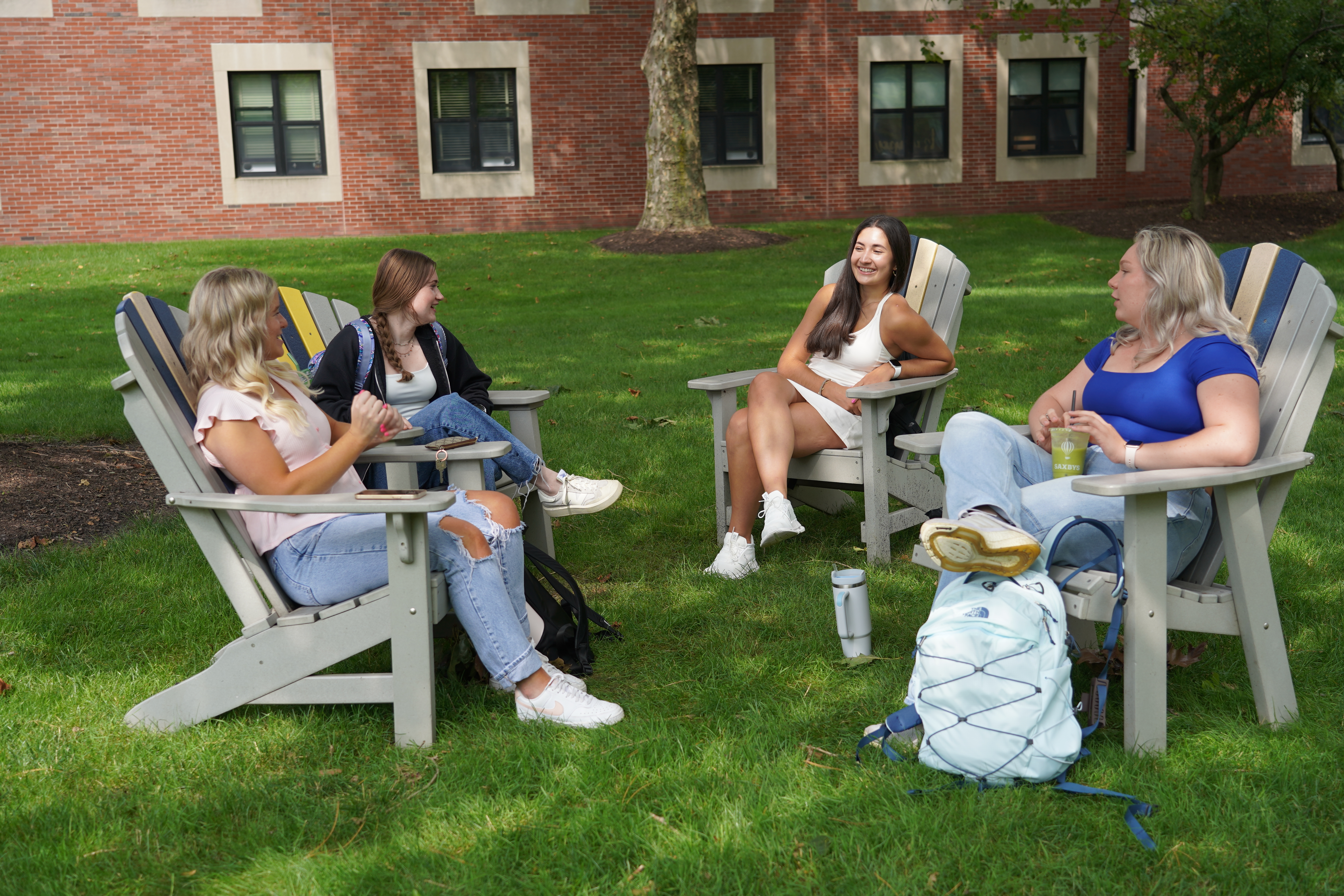 female students sitting in adirondack chairs outside
