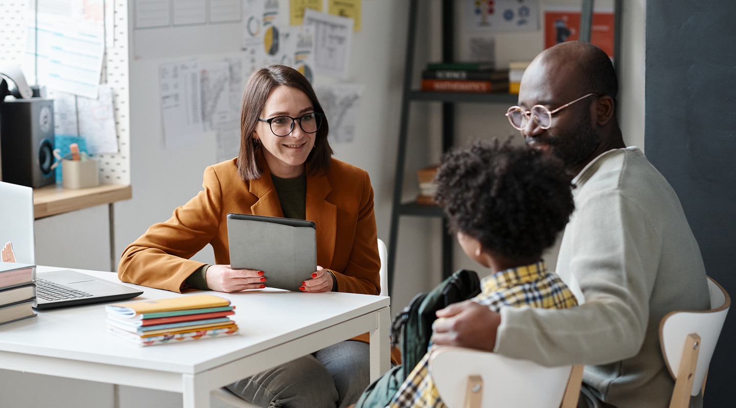 Picture of female school counselor meeting with young client and his father