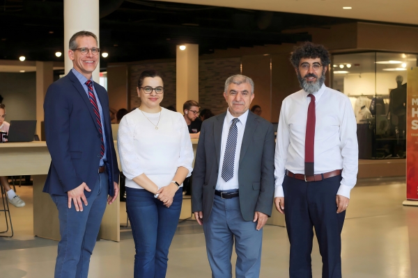 four people standing and smiling at the camera