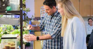 Brown haired professor explaining plant biology to young blonde female student