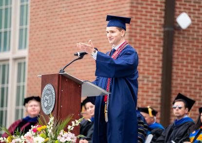 Tate Farinacci speaking at JCU's 2025 undergraduate commencement ceremony.